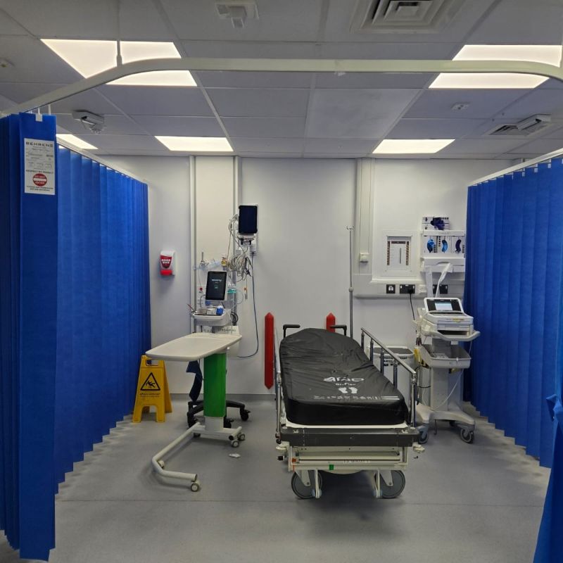 hospital ward bay with blue curtains and a bed